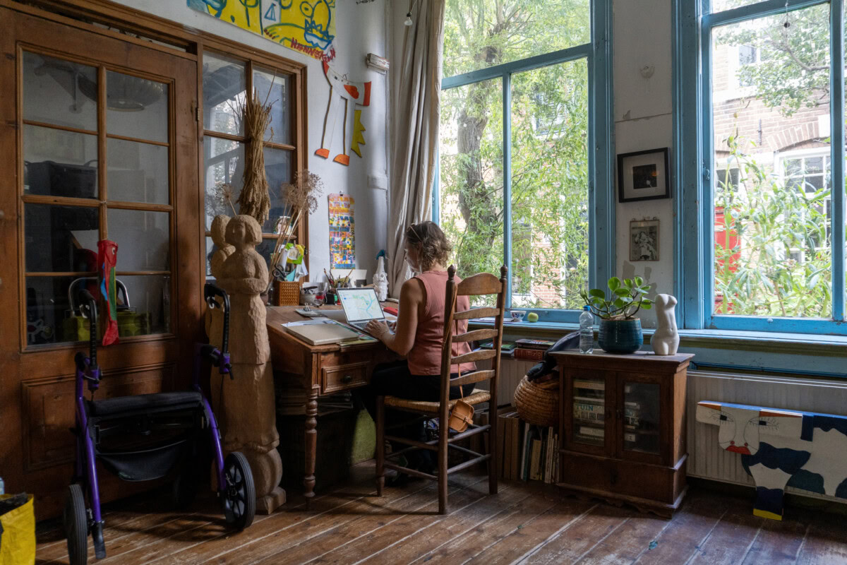 Jorinde Kuiper in haar creatieve atelier met grote ramen en kleurrijke decoraties.